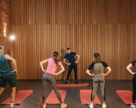 People stretching on yoga mats during a fitness class indoors.